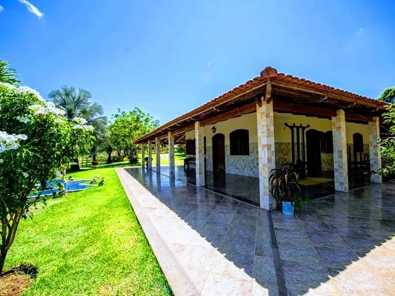 Clínica de Recuperação em Itaúna - MG Casa térrea de telhado cerâmico com varanda de piso escuro e pilares revestidos de pedra, ao lado de um gramado